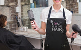Hair Stylist wearing LOVE IS IN THE HAIR apron from Trendy Salon Aprons